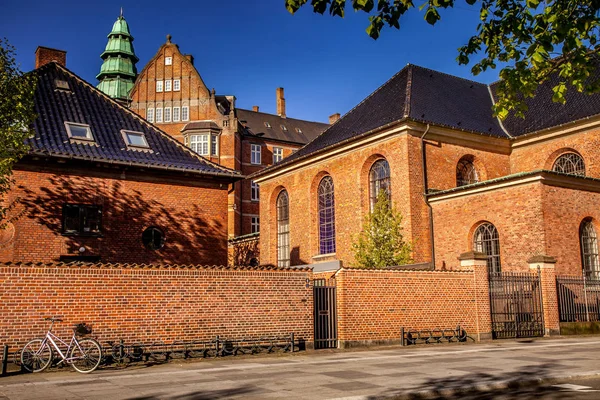 Bellissimo edificio storico con muro di mattoni e biciclette parcheggiate su strada accogliente in copenhagen, denmark — Foto stock