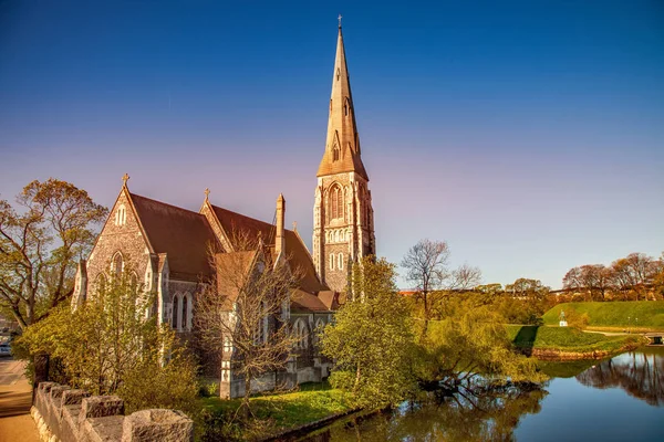 Laghetto tranquillo con vegetazione verde vicino a bella vecchia chiesa nella giornata di sole, copenhagen, denmark — Foto stock