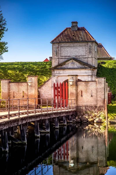 Ponte di legno vuoto e cancelli con lanterne e vecchia struttura di fortificazione riflessa in acqua, copenhagen, denmark — Foto stock