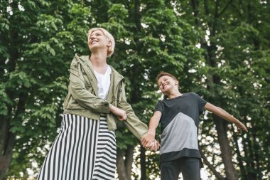 mutlu anne ve oğlu elele ve birlikte Park'ta yürüyordunuz düşük açılı görünümü