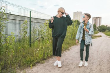 Anne ve oğlu birlikte beyzbol sopası ve çocuk yeme elma tutan kadın yere yolda yürürken gülümseyen 