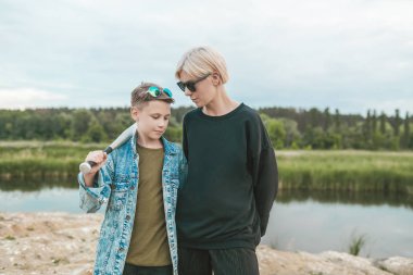 güzel anne ve oğlu lake yakınındaki beysbol sopası ile ayakta güneş gözlüğü