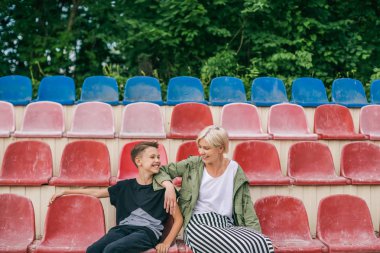 mutlu anne ve oğlu birbirlerine birlikte stadyum koltukları üzerinde otururken gülümseyen