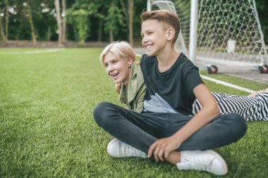 neşeli anne ve gülüyor ve uzak birlikte yeşil çimenlerin üzerinde dinlenme süre seyir oğlu