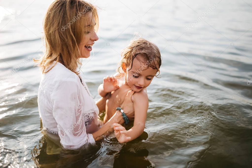 happy mom holding daughter in river