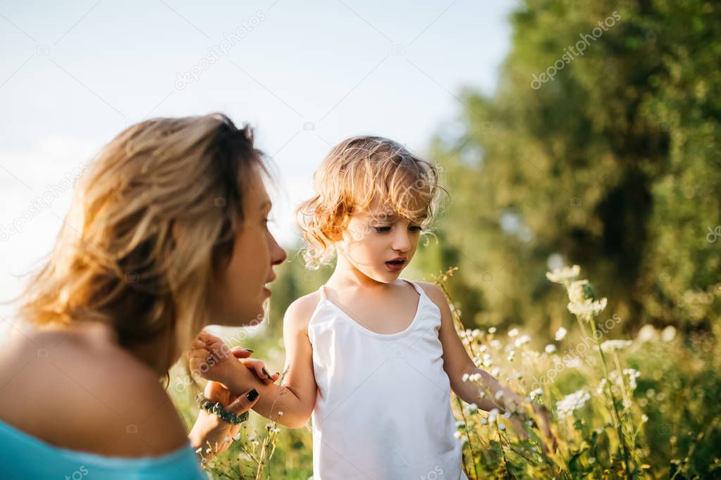 mother and child looking at flowers in green field