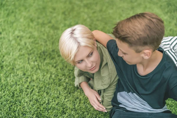 Vista ad alto angolo di felice madre e figlio che si abbracciano e si guardano mentre sono sdraiati insieme sull'erba — Foto stock