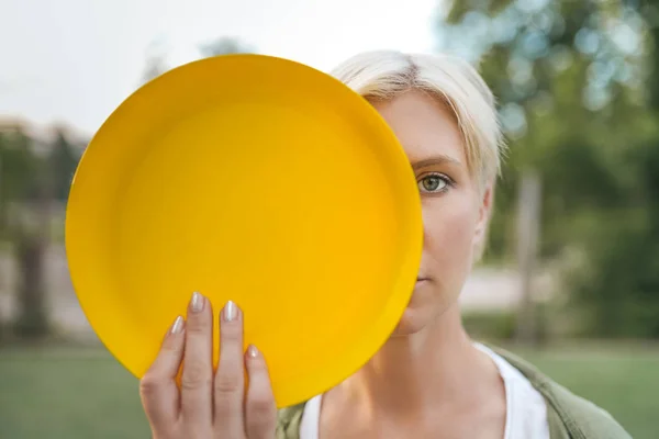 Beautiful blonde woman holding yellow flying disk and looking at camera — Stock Photo