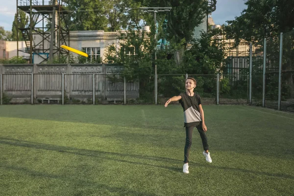 Visão comprimento total do menino jogando disco voador no gramado verde — Fotografia de Stock