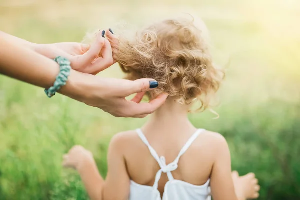 Immagine ritagliata della madre che tocca i capelli ricci del bambino all'aperto — Foto stock