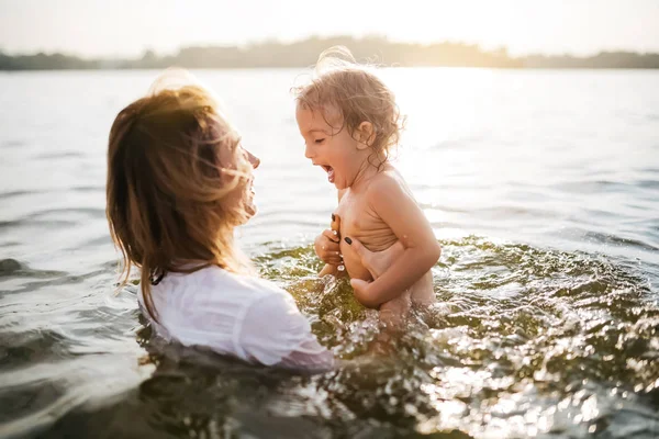 Glückliche Mutter hält schreiende Tochter im Fluss — Stockfoto