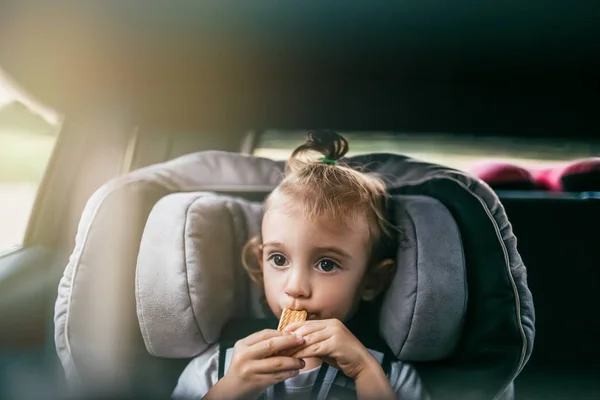 Adorável criança comer biscoitos no carro e olhando para longe — Fotografia de Stock
