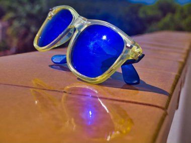 Sarı bir duvar üzerinde güneş gözlüğü