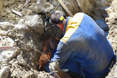 İşçi siperdeki su borusundaki sızıntıyı yok ediyor. Kamu hizmeti. Vodokanal.