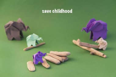 Origami filleri yeşil arka planda renkli kağıtlardan yapılmıştır. Kağıt ve orman koruma kavramı. Aile ve çocukluk. Mockup, boşluğu kopyala.