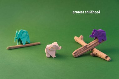 Origami filleri yeşil arka planda renkli kağıtlardan yapılmıştır. Kağıt ve orman koruma kavramı. Aile ve çocukluk. Mockup, boşluğu kopyala.