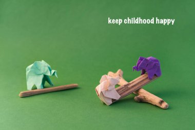 Origami filleri yeşil arka planda renkli kağıtlardan yapılmıştır. Kağıt ve orman koruma kavramı. Aile ve çocukluk. Mockup, boşluğu kopyala.