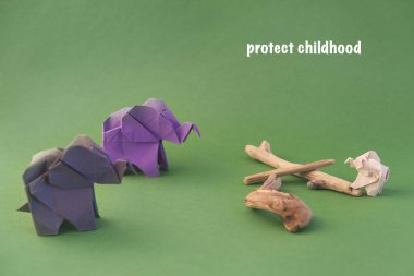 Origami filleri yeşil arka planda renkli kağıtlardan yapılmıştır. Kağıt ve orman koruma kavramı. Aile ve çocukluk. Mockup, boşluğu kopyala.