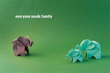 Origami filleri yeşil arka planda renkli kağıtlardan yapılmıştır. Kağıt ve orman koruma kavramı. Aile ve çocukluk. Mockup, boşluğu kopyala.
