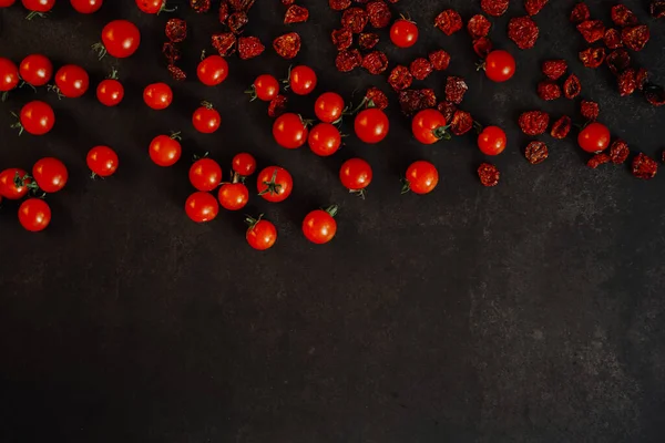 dried and fresh cherry tomatoes on a black background free space for text