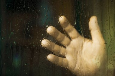 Yağmur ile bir pencerede bir adamın elini bırakır. Depresyon kavramı.