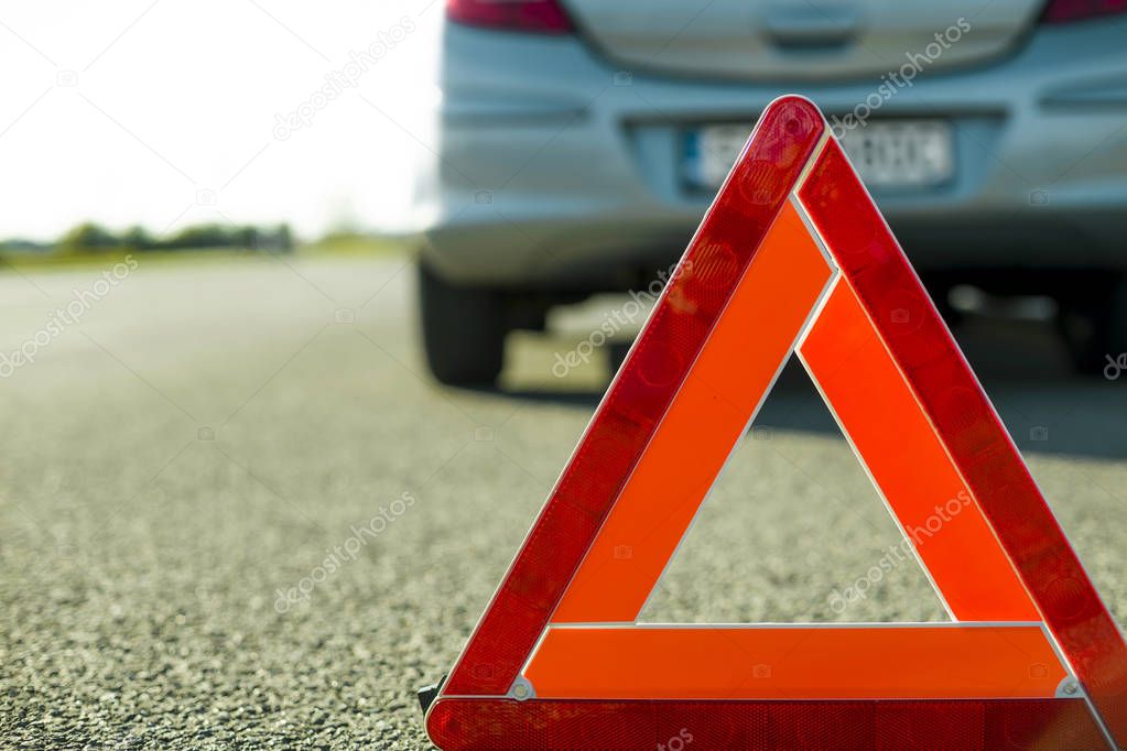 A warning triangle on the background of a damaged car