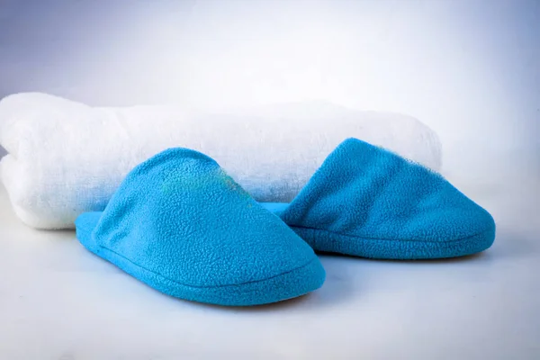 Blue slippers on a white towel on a white-blue background