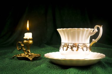 Yeşil bir bez karşı bir retro Kupası şamdanla içinde yanan mum