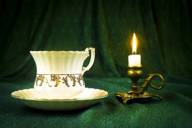 Yeşil bir bez karşı bir retro Kupası şamdanla içinde yanan mum