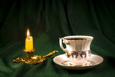 Yeşil bir bez karşı bir retro Kupası şamdanla içinde yanan mum