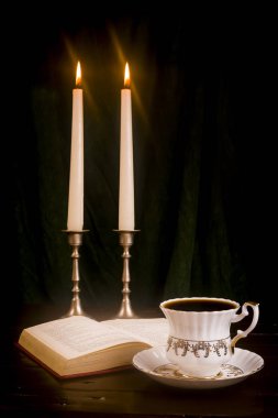 Retro bir fincan ve anakartları arka plan üzerine açık bir kitap şamdanla içinde yanan mum