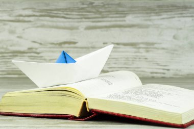 Açık bir kitap üzerinde duran bir kağıt gemi