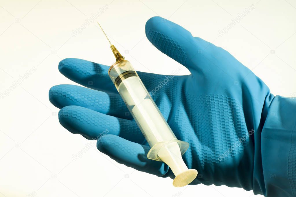 Syringe on an open hand in a blue glove on a white background, isolated