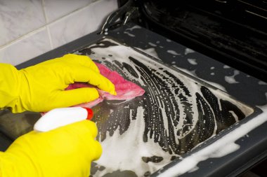 İnsan elinde bir sarı lastik eldiven fırın gaz kapak yıkama bez soba