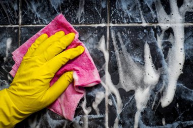 İnsan elinde bir sarı lastik eldiven döşenmiş bir pembe bez yıkar