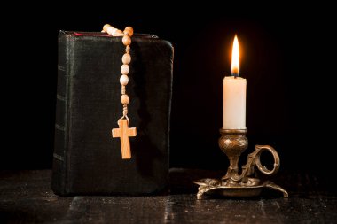 Tespih kitap ve siyah bir zemin üzerine bir mum yanan bir mum