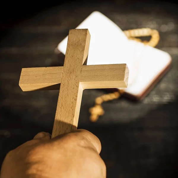 The cross held in the hand against the background of the book wi