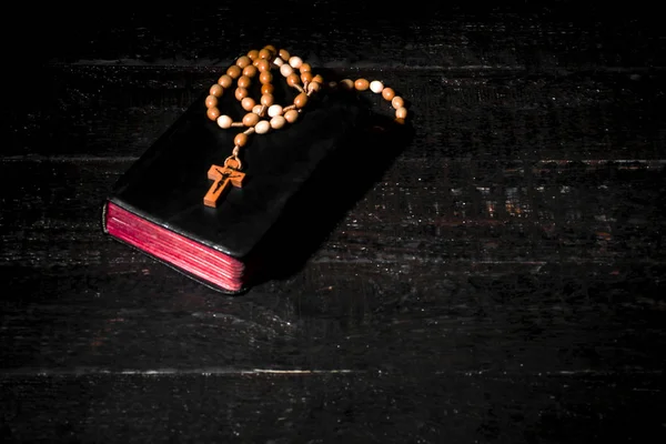 Ein helles Buch mit einem Rosenkranz auf dunklen Brettern — Stockfoto