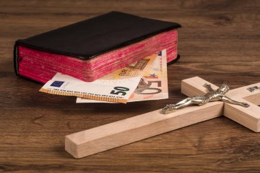 Bir arka plan bir kitabın kurullarında euro banknot ile yatan bir haç