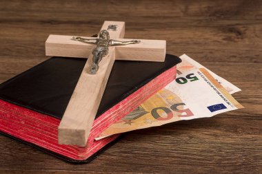 Bir arka plan bir kitabın kurullarında euro banknot ile yatan bir haç