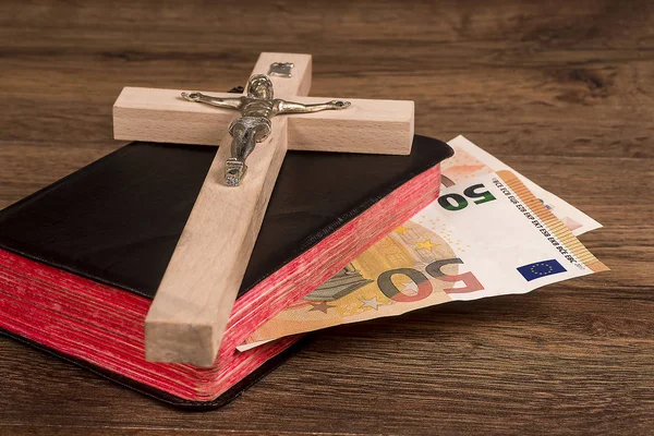 Bir arka plan bir kitabın kurullarında euro banknot ile yatan bir haç