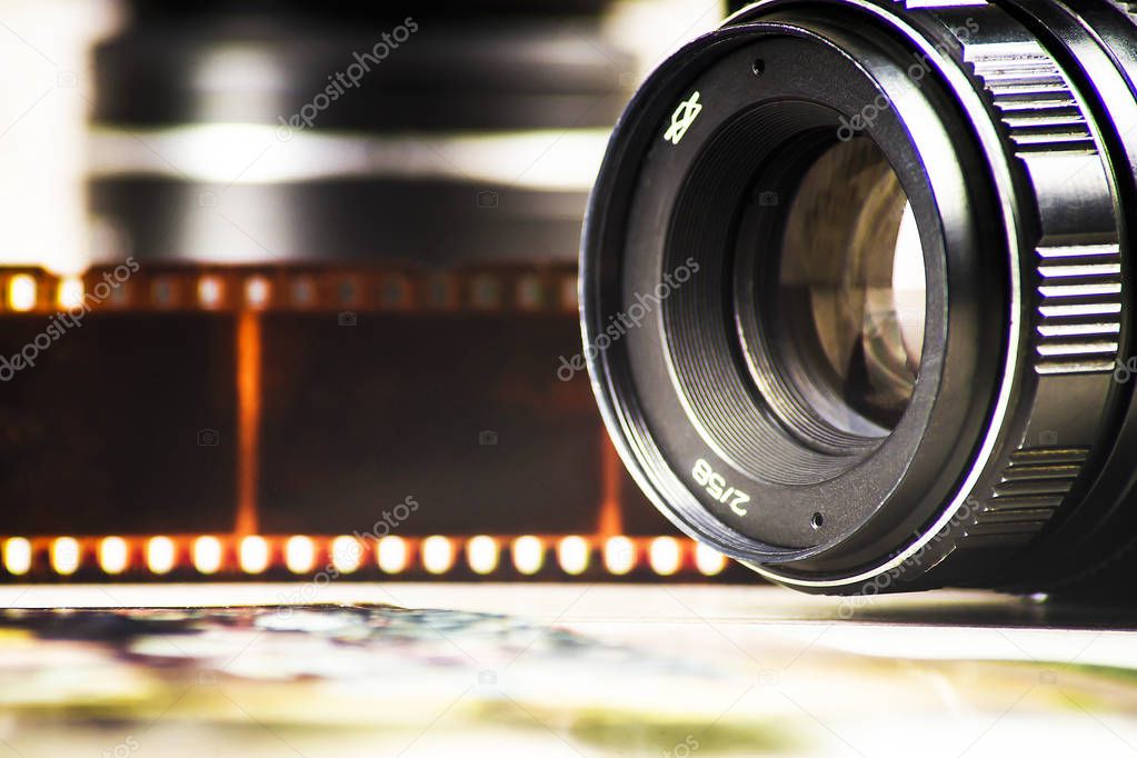 Concept of analog photography, camera on a background of colored negatives and a lens