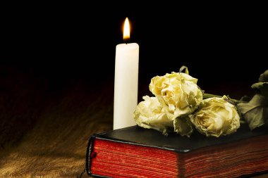 Eski kitap, solmuş gül ve yanan bir muma