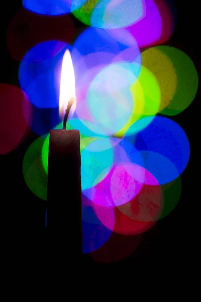 Brennende Kerze auf buntem Bokeh-Hintergrund — Stockfoto