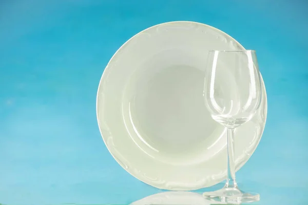 Une assiette et un verre sur fond bleu — Photo