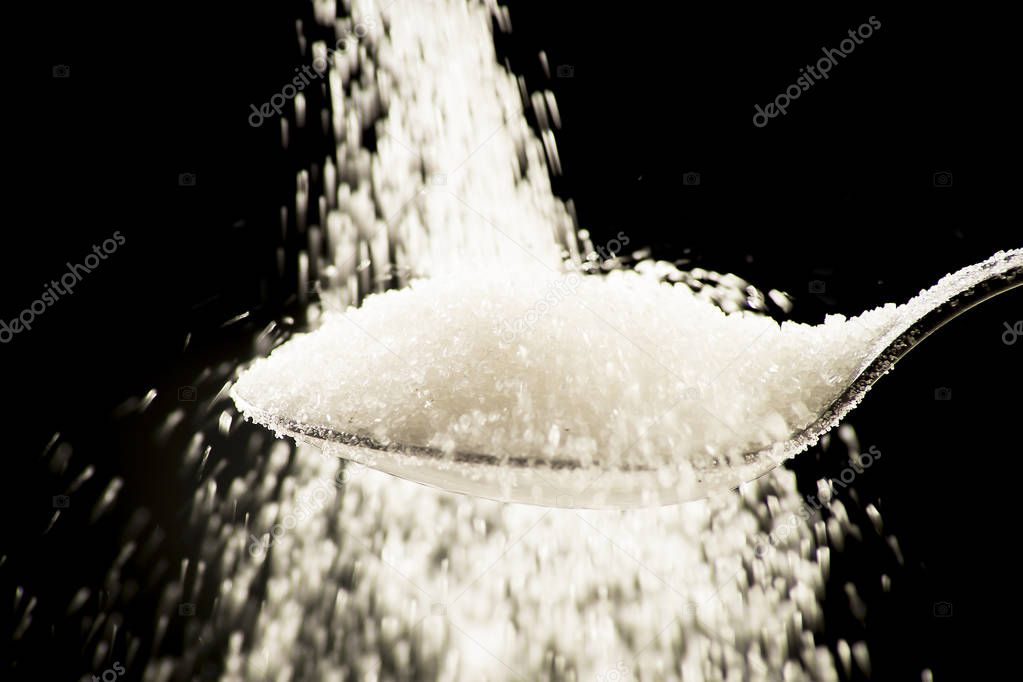 Sugar on a teaspoon on a black background