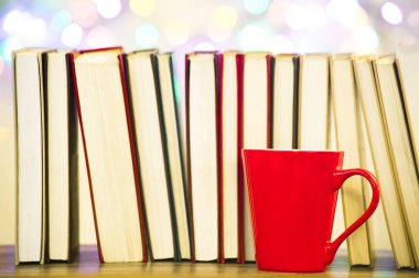 Bir sıra kitap bir arka planda bir kalp ile kırmızı bir kupa, bir