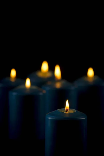 Lit velas azuis em um fundo preto — Fotografia de Stock