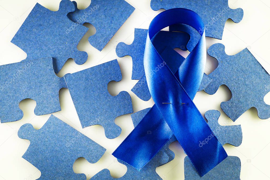 A blue ribbon on a background of scattered jigsaw puzzles