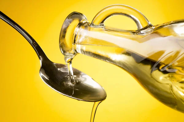Pouring oil from the bottle into a spoon — Stock Photo, Image